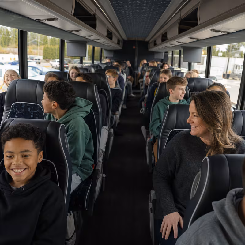 Group boarding a white charter bus for School Transportation transportation in Fremont